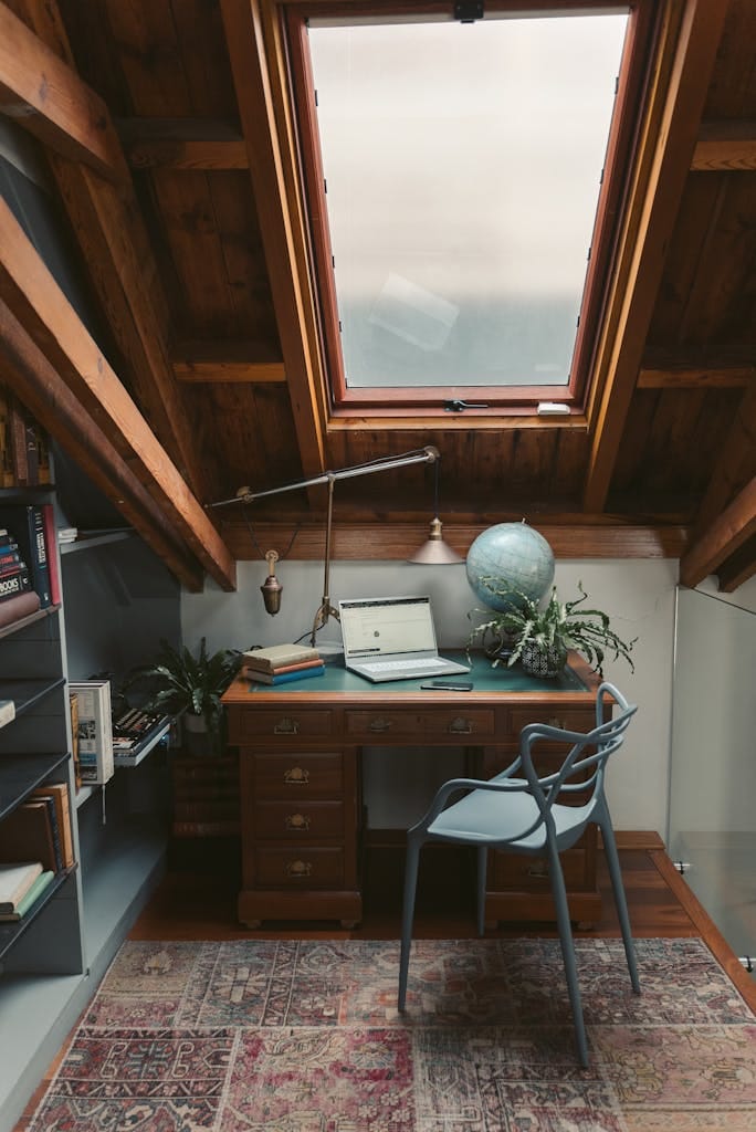 A cozy attic office space with a vintage desk, globe, and books under a skylight. Mixing Styles