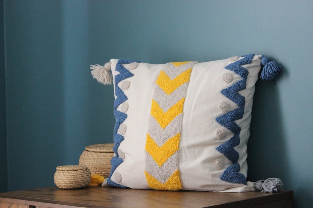 A modern throw pillow with chevron pattern and tassels, perfect for cozy interiors.