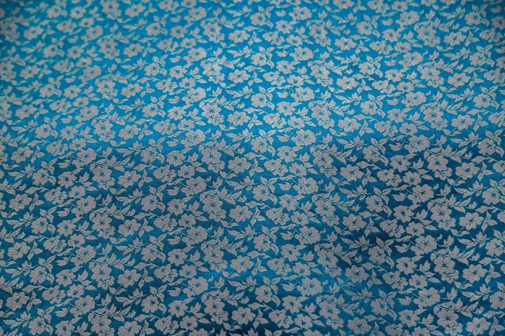 A blue fabric with a small white floral pattern.
